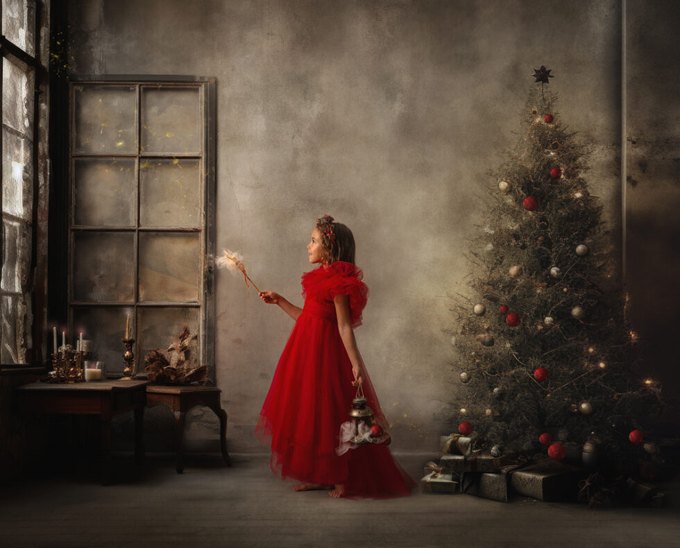 Fotografía chica joven con vestido rojo en sala mágica con árbol de navidad y varita