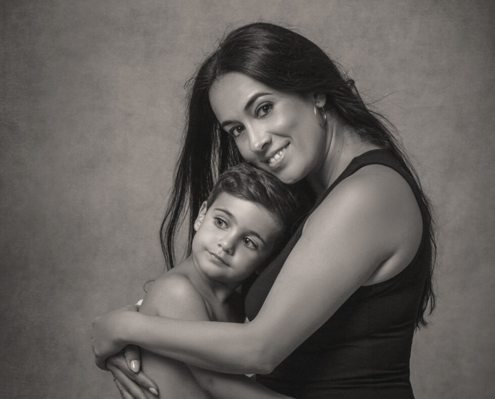 Fotografía madre e hijo abrazados en fondo grisáceo