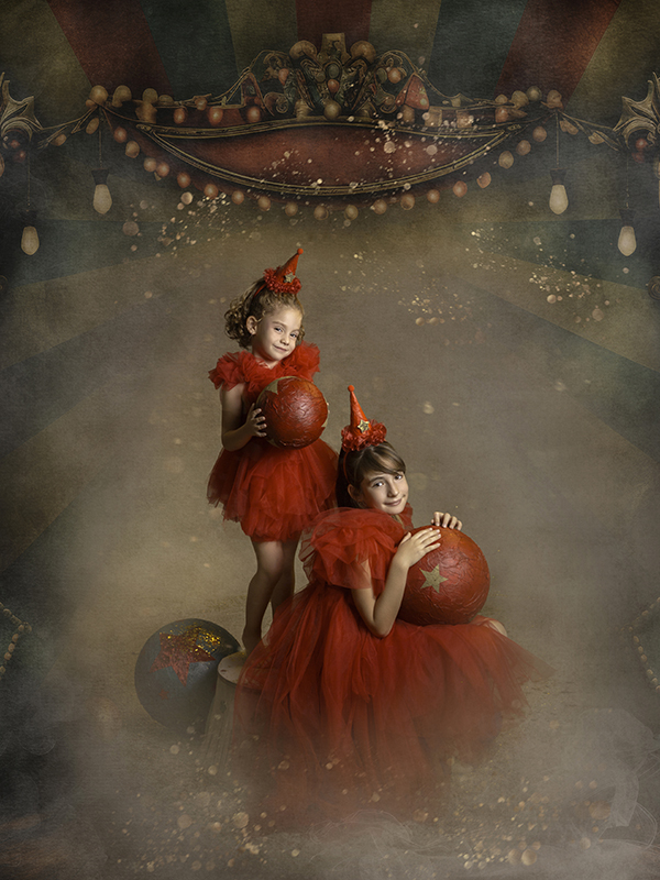 Fotografía de dos niñas con vestidos rojos mirando a la cámara en un circo