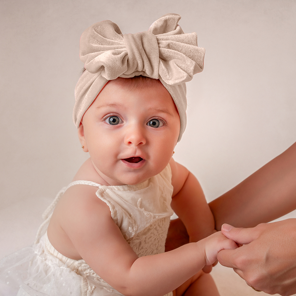 Magicasfotos MamaYYo (20) Fotografía de una bebé con vestido blanco y lacito mirando a la cámara